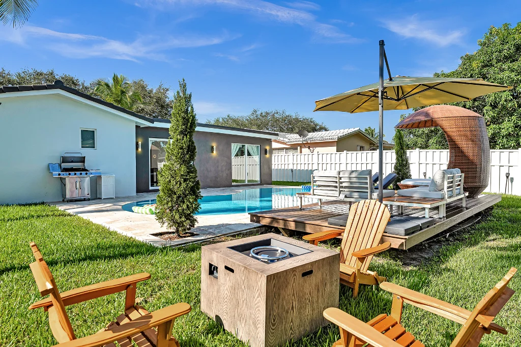 Backyard with pool, lounge deck, umbrella seating, fire pit, and outdoor grill.