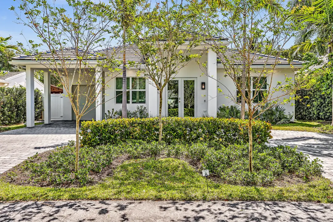 Front view of white single-story home with landscaped yard and paved driveway suitable for long-term property management.