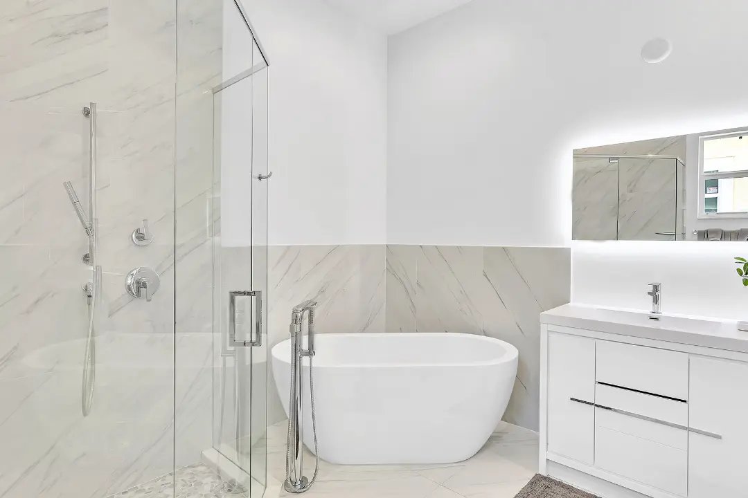 Modern bathroom with glass shower, freestanding tub, and white vanity in a long-term rental home.