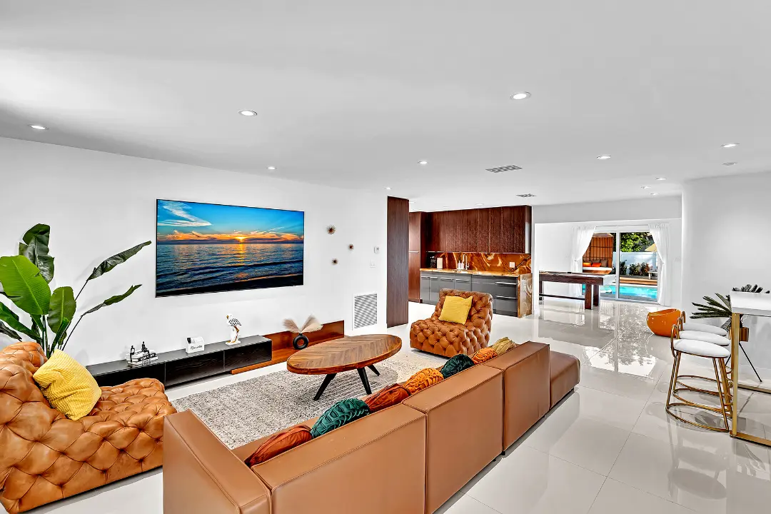 Spacious living room with brown leather seating, wall-mounted TV, and bar area in a long-term rental home.