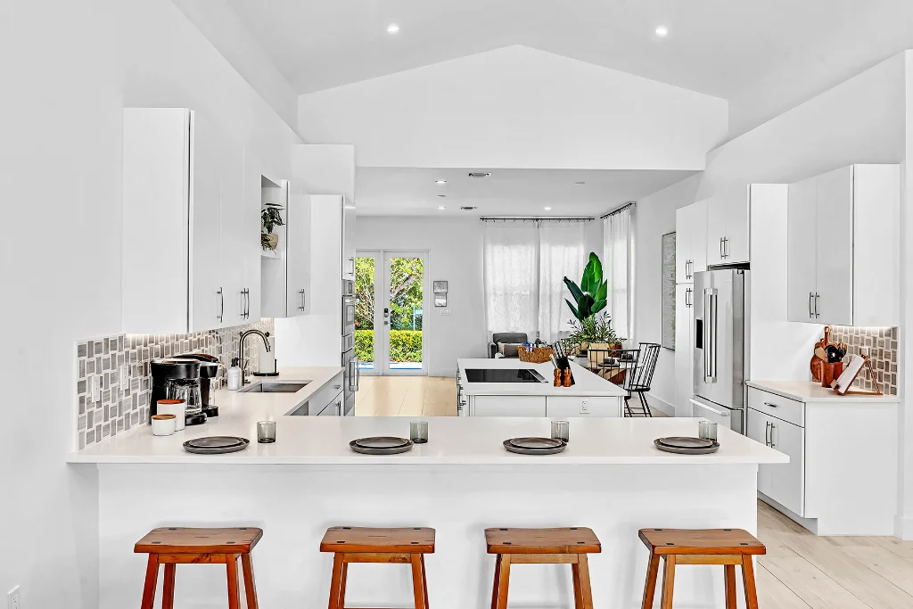 Bright modern kitchen with white cabinets, island seating, and open layout to living area