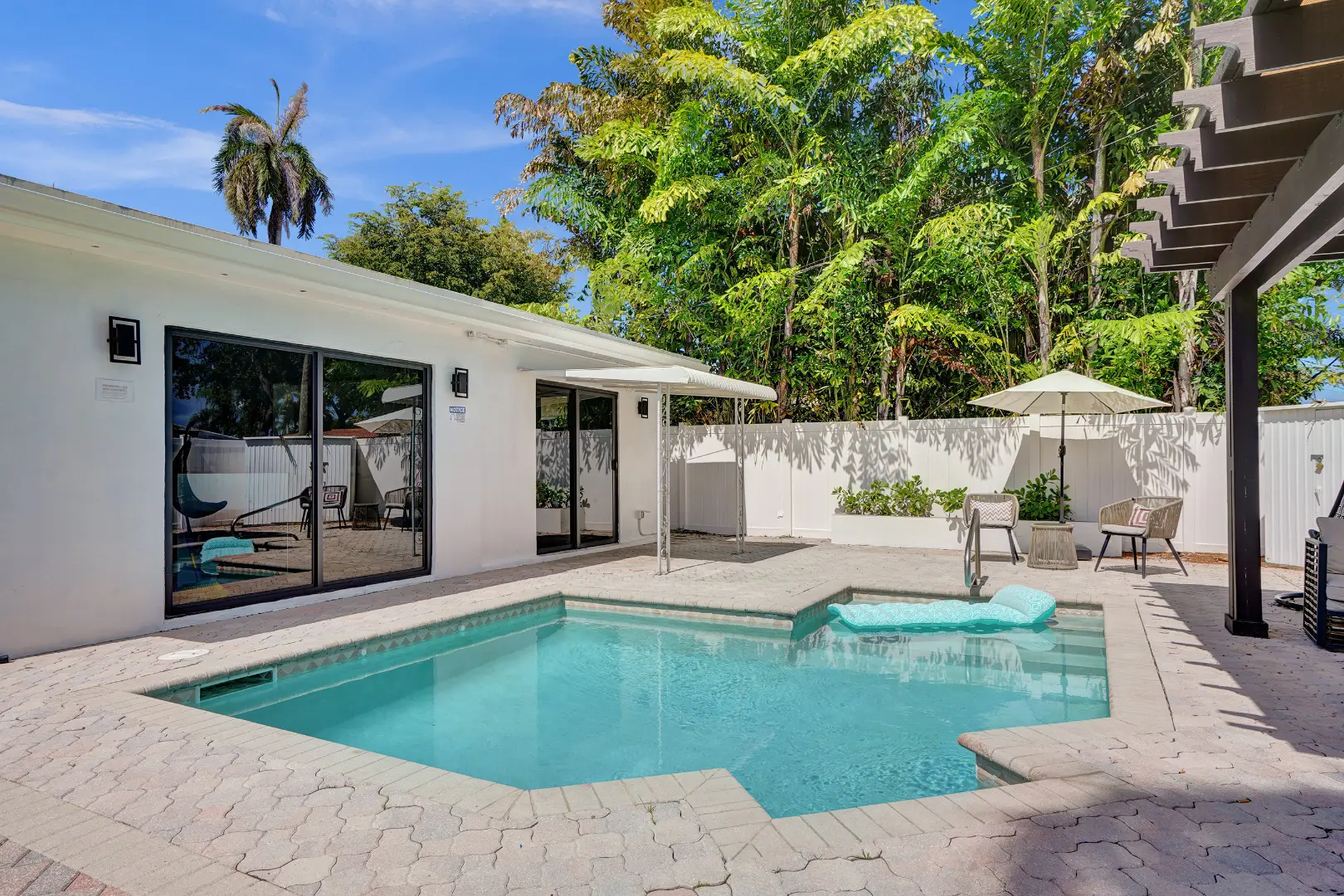 Private backyard pool with patio seating and lush tropical landscaping