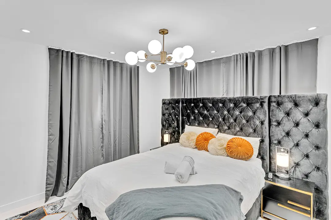 Bedroom featuring tufted velvet headboard, globe chandelier, and accent pillows in a vacation rental.