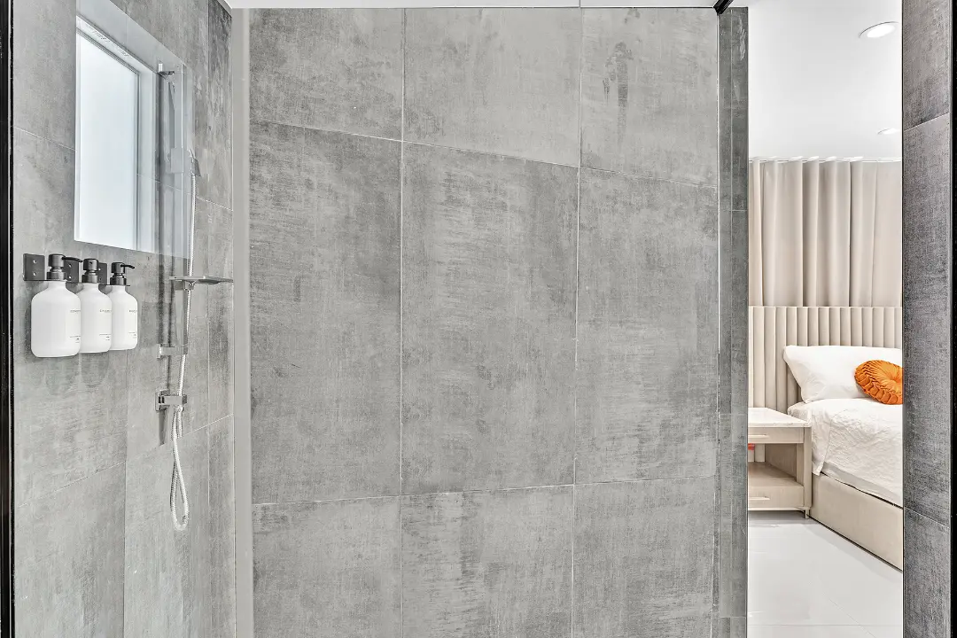 Walk-in shower with gray tile walls, mounted toiletries, and chrome fixtures in a vacation rental.