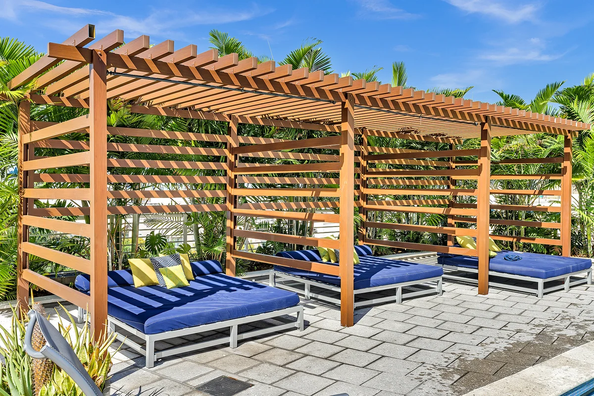 Luxury pergola with blue lounge chairs and tropical landscaping