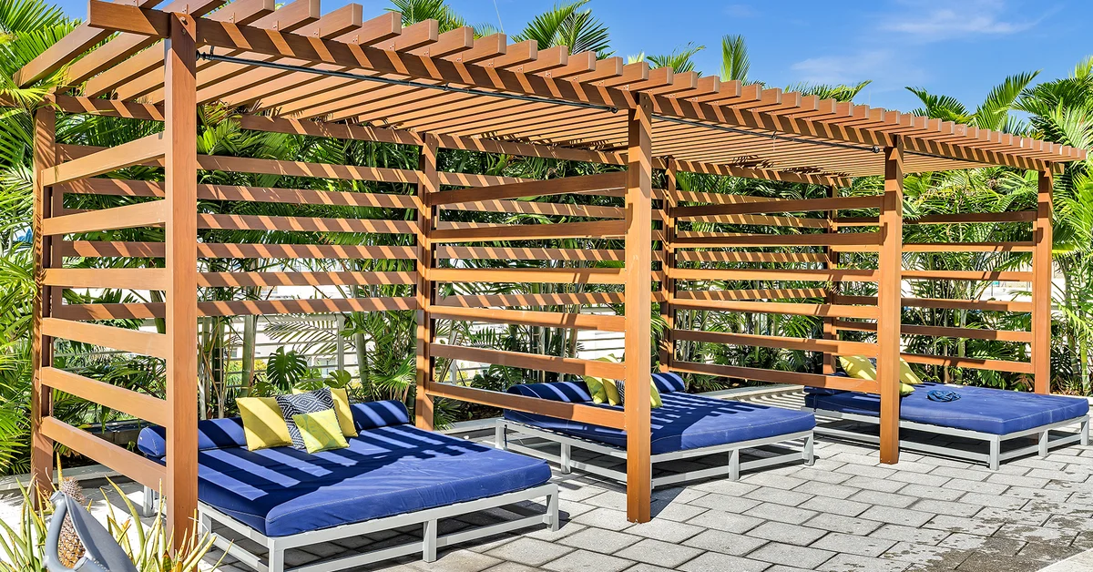 Luxury pergola with blue lounge chairs and tropical landscaping